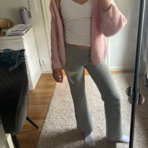 Grå mjukisbyxor med vit stjärna från Kappahl - Grå mjukisbyxor från Kappahl med en stor vit stjärna på ena benet. Byxorna har resår i midjan och är raka i modellen, perfekta för en avslappnad stil. Lite noppriga