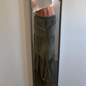 Grön långkjol med volang - Säljer en snygg grön långkjol med volangdetaljer och resår i midjan. Jag har plockat bort båda tofsarna på snöret💞