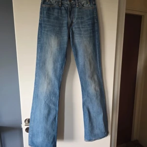 Blå bootcut jeans från Acne Jeans - Säljer ett par klassiska blå bootcut jeans från Acne Jeans. Jeansen har normal passform, fem fickor och stängs med knapp och dragkedja. Perfekta för dig som gillar en tidlös och avslappnad stil.