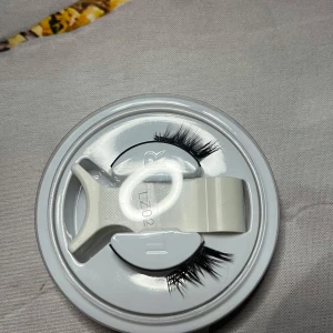 Svarta lösögonfransar med applikator - Säljer ett par svarta magnetiska lösögonfransar i plastförpackning, medföljer en vit applikator för enkel applicering. Fransarna är täta och ger en dramatisk look, perfekta för att framhäva ögonen. Ordinarie pris: 60 kr 