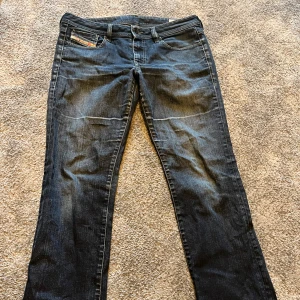 Mörkblå jeansbyxor från Diesel - Snygga mörkblå jeans från Diesel med klassisk femficksdesign. Byxorna har raka ben och detaljer som Diesel-logga på myntfickan och bakfickan. Perfekta för en avslappnad stil.
