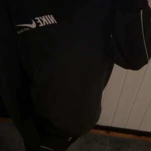 Svart sweatshirt från Nike - Säljer en svart sweatshirt från Nike med vit logga och texten 'Just do it.' på bröstet. Tröjan har långa ärmar med vita detaljer längs sidorna. Perfekt för en sportig och avslappnad stil.