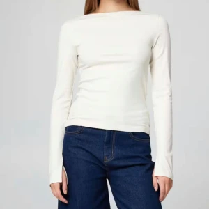 Vit långärmad topp i bomull - Enkel och stilren vit långärmad topp med rund halsringning. Tillverkad i mjuk bomull som sitter skönt mot kroppen. Perfekt att matcha med jeans eller kjol för en clean look. Passformen är normal och modellen är klassisk utan detaljer.