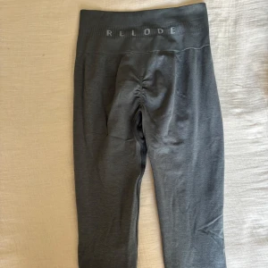 Grå/gröna Prime Scrunch leggings från Relod - Snygga mörkgrå/gröna leggings från Relode i storlek XXS. De har hög midja, ribbad linning och scrunch-detalj bak för extra form. Perfekta för träning eller chill, med stretchigt och mjukt material som sitter skönt hela dagen.