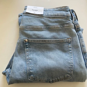 Ljusblå straight jeans från H&M - Säljer ett par ljusblå jeans från H&M i straight modell med regular fit. Klassisk femficksdesign och snygg tvättad denim. Oanvända 