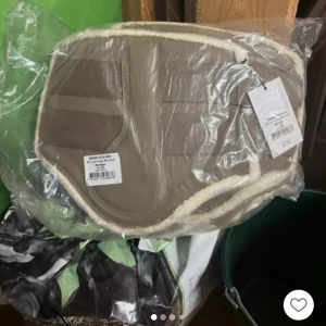 Ps benskydd  - Säljer en beige axelväska med mjuka fuskpälsdetaljer längs kanterna. Väskan har en stilren och enkel design med praktiska fack på utsidan. Perfekt för dig som gillar en mysig och trendig look.