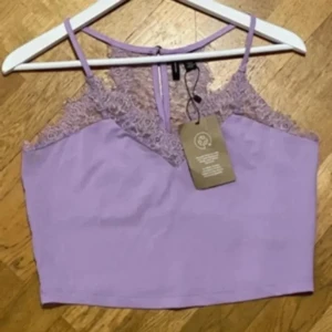 Lila spetslinne från Vero Moda!  - Säljer ett lila linne från Vero Moda  med vackra spetsdetaljer vid axlarna och ryggen. Linnet har smala axelband och en elegant design som passar perfekt för sommardagar. Färgen är syrenlila. 