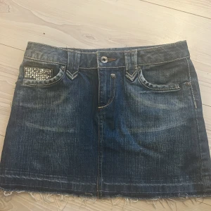 Jeanskjol med glittriga detaljer - Säljer denna finna jeanskjolen då den tyvärr inte satt så bra på mig. Den är i storlek 34 och har midjemåttet 35 cm rakt över.
