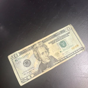 Amerikansk 20 dollar sedel - amerikansk 20-dollarsedel med tydliga detaljer på både fram- och baksida. Sedeln har synliga säkerhetsdetaljer och är något sliten i kanterna. Perfekt för dig som samlar på utländska sedlar eller är intresserad av valuta och design.