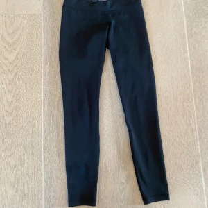 Svarta tights från Aim'n XXS - Svarta tights från Aim'n i modellen Black Edge Core. De har låg midja och är tillverkade i stretchigt material med 73% polyester och 27% spandex.  logga på benet och tight passform