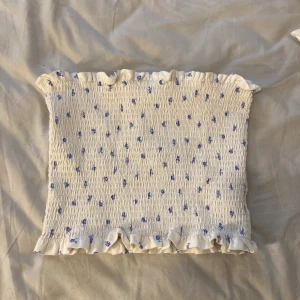 Vit blommig tubtopp - Fin tub topp från H&M, den är i storlek L men den är jätte liten i storlek! Den sitter bra på mig som har storlek S i vanliga fall!💕