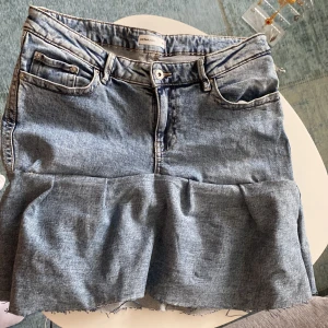 Jeanskjol med volang från Perfect Jeans - Säljer en ljusblå jeanskjol från Perfect Jeans i storlek 40. Kjolen har klassiska fickor fram och bak, snygga kontrastsömmar och en bred volang nertill för extra edge. Rå kant längst ner för en cool, avslappnad look. Perfekt för dig som gillar denim vibes!