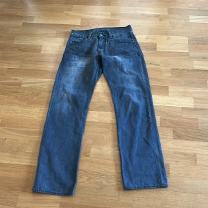 Levi's grå jeans straight fit med medelhög midja - Klassiska grå Levi's 514 jeans med raka ben och normal passform. Jeansen har fem fickor, knappgylf och snygga detaljer på bakfickorna. Tillverkade i slitstarkt denim med en lätt tvättad look. Storlek 31x32.