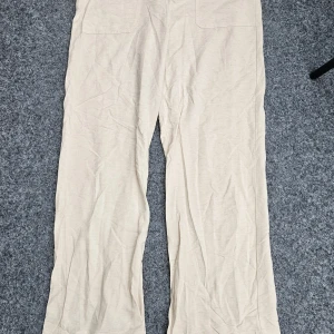 Beiga linnebyxor  och viscos från Gina Tricot - Snygga beiga linnebyxor från Gina Tricot i rak och loose passform. Byxorna har hög midja och stora fickor framtill. Perfekta för en chill och stilren look under varmare dagar. Storl.M