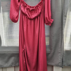 Rosa/ cerise  långklänning med puffärm storl.M - Säljer en snygg rosa långklänning med puffiga trekvartsärmar och resår vid axlar och ärmslut. Klänningen har en slits på sidan och är gjord i ett mjukt, lätt material som faller fint. Perfekt för dig som gillar romantisk och trendig stil. Har använt den en gång på gravidfotografering. Så är ingen geavudklänning men med vidden funkar den till det också.