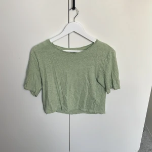 Ljusgrön croppad topp från Lindex - Enkel och stilren ljusgrön croppad topp från Lindex. T-shirten har korta ärmar, rund halsringning och är tillverkad i mjuk bomull. Perfekt för en avslappnad look och lätt att matcha med jeans eller kjol.