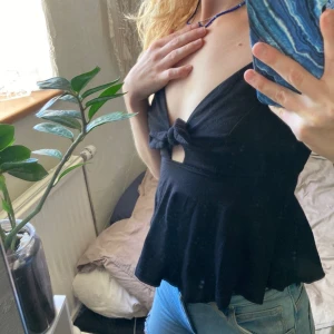 Svart knytlinne med v-ringning - Supersnygg svart linne med djup v-ringning och knyt framtill. 