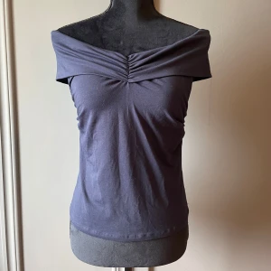 Mörkblå offshoulder topp Holly & Whyte - Snygg mörkblå offshoulder topp från Holly & Whyte by Lindex. Toppen har en bred, vikt kant över axlarna och lätt rynk framtill vid bysten. Den är aldrig använd, ny utan prislapp!