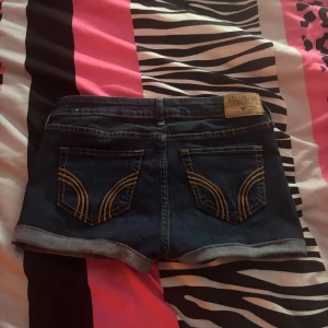 Mörkblå jeansshorts från Hollister - Snygga mörkblå jeansshorts från Hollister. Dem är perfekta nu för sommaren. Jeanstyget är stretchigt vilket gör att de sitter bättre. Dem är aldrig använda av mig men när jag köpte dem så var den uppvikts kanten redan syd så det är inte jag som har gjort sömmen. Skriv om fler bilder men kommer nog inte att gå ner så mycket i pris då dem är helt fläckfria och ser helt nya ut.