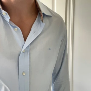 Burberry skjorta  - Inga som helst defekter, storlek 42 vilket motsvarar ungefär L. Stor på mig som är 180,75 kg. Kom med frågor! Kanske ser ut som en missfärgning eller likande men det är bara galgen som syns igenom! 
