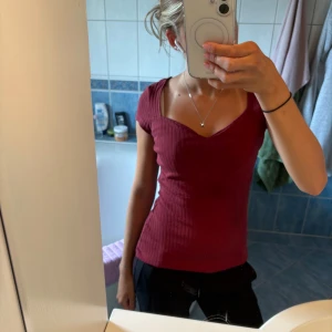 Vinröd ribbad topp från Anna Field - Vinröd ribbad topp med söt v-ringning och korta ärmar från Anna Field. Figurnära passform och stretchigt material som sitter snyggt. Perfekt att styla med jeans eller kjol för en trendig look.