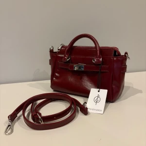 Vinröd handväska från Stradivarius - Oanvänd vinröd handväska i skinnimitation från Stradivarius. Väskan har silverfärgade metalldetaljer och avtagbart axelband ☀️ 