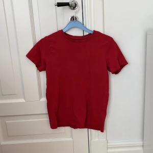 Röd t-shirt från Zalando Essentials - Enkel och stilren röd t-shirt från Zalando Essentials. Klassisk rund halsringning och korta ärmar. Tillverkad i mjuk bomull som är skön mot huden. Perfekt för dig som gillar basic plagg med färg.