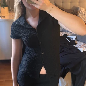 Skjort topp från Gina tricot  - En svart topp från Gina Tricot i storlek S. Toppen är v-ringad, har en krage som en skjorta, fyra knappar och avslutas med ett slits. Jag har aldrig hittat ett tillfälle att använda den men prislappen har jag klippt av. Men som ny helt enkelt. Har du några frågor så bara hör av dig!💗☺️