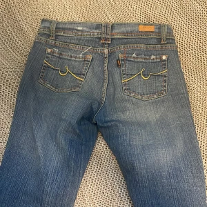Blå bootcut jeans med slitna detaljer - Blå lågmidjide jeans. Väldigt stretchiga som man ser på sista bilden, de ända defekterna är slitningarna. Pris kan diskuteras😁eftersom de är så stretchiga så passar de storlek xs-L men skulle säga att de passar som bäst till S och M
