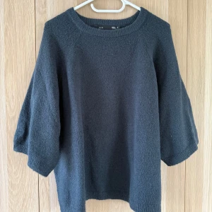 Mörkblå stickad tröja  - Mysig mörkblå stickad tröja från Lager 157 med rund halsringning och trekvartsärmar. Tröjan har en enkel och clean design med ribbade muddar vid hals och ärmslut. Perfekt för lager-på-lager och chill vibes.