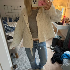 Quiltad vit jacka i loose fit - Säljer en supermjuk quiltad jacka i vit med oversized passform. Jackan har långa ärmar, tryckknappar framtill och coola sömmar som ger en trendig look. Perfekt att slänga på sig över en hoodie eller t-shirt för en chill vibe.