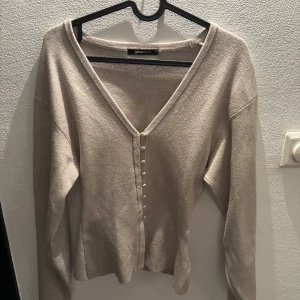 Beige Knitted cardigan från Gina Tricot - Superfin beige kofta från Gina Tricot i storlek XS. Koftan har v-ringning, långa ärmar och snygga klädda knappar framtill. Mjuk och skön, perfekt att slänga på sig över ett linne eller t-shirt. Enkel att styla till både jeans och kjol.