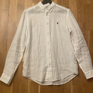 Vit linneskjorta från Polo Ralph Lauren - Fräsch vit skjorta i linne från Polo Ralph Lauren med klassisk button-down krage och broderad marinblå logga på bröstet. Bara använd en gång. Storlek XL (18-20) i barnstorlek vilket är S ungefär. Hör gärna av er om ni vill ha mått eller har några frågor 🤗