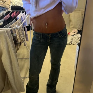 Mörkblå bootcut jeans låg midja - Snygga mörkblå jeans med bootcut och låg midja. Klassisk femficksmodell med lätt slitning och raka ben som blir vidare nertill. Perfekta för dig som gillar en retro vibe och vill ha ett par jeans som sticker ut lite extra.