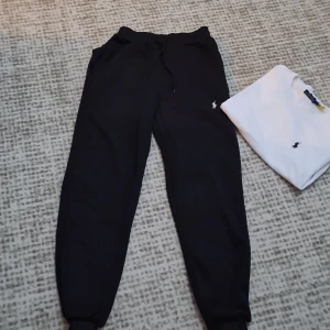 Svarta mjukisbyxor Polo Ralph Lauren - Svarta mjukisbyxor från Polo Ralph Lauren med klassisk broderad logga på benet. Byxorna har dragsko i midjan och muddar vid bensluten för en skön och avslappnad passform. Perfekta för chill eller streetwear.