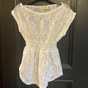 Vit spetsblus från Pink Love - Supersöt vit blus från Pink Love med blommigt spetsmönster och elastisk midja. Spetsen ger en romantisk och fräsch vibe, och den luftiga modellen är både bekväm och snygg.💕