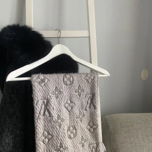 Grå Louis Vuitton halsduk i ull och silke - Snygg grå halsduk från Louis Vuitton med ikoniskt monogrammönster. Halsduken är stickad i en blandning av ull och silke, vilket gör den både mjuk och lyxig. Perfekt accessoar för att lyfta din outfit med en exklusiv touch.