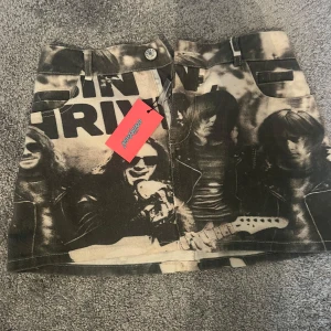 Svart och beige jeanskjol från Edikted - En extremt cool kort jeanskjol från Edikted med svart och beige fotoprint av rockband och text. Lappen sitter kvar och aldrig använd. Priset kan såklart diskuteras.