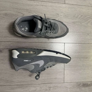 Nike Air Max 90 grå sneakers strl 45.5  - Snygga Nike Air Max 90 sneakers i olika grå nyanser med vit sula och klassisk synlig Air Max-dämpning. Skorna har mesh och syntetmaterial, rund tå och snörning. Perfekta för dig som gillar stilrena och sportiga vibes. Nypris 2k, ställ frågor om ni är osäkra! 👍 