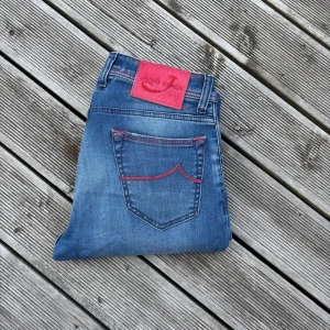Jacob Cohen Type 688 Comfort - Omsydda någon centimeter nertill! Snygga blå jeans från Jacob Cohen i modell 688 Comfort. Jeansen har röda kontrastsömmar, unika broderade detaljer och patch baktill. Klassisk femficksdesign och bekväm passform. Tillverkade i mjukt bomullstyg med stretch för extra komfort. Kom gärna med frågor🙌 Förmodligen unisex med tanke på färgen men inte säker