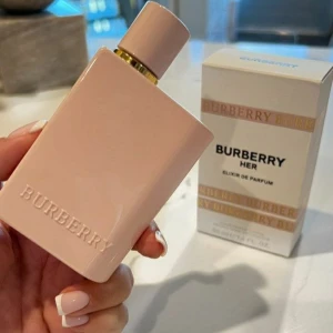 Burberry Her Elixir de Parfum 30ml oanvänd  - Burberry Her Elixir de Parfum i en stilren, ljusrosa flaska med guldiga detaljer. Flaskan är rektangulär och har en minimalistisk design med Burberry-loggan i relief. Volymen är 30 ml och parfymen är tillverkad i Spanien.