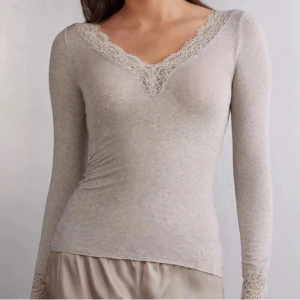 Beige långärmad topp med spets - Supersnygg beige långärmad topp med v-ringning och fina spetsdetaljer vid halsringningen och ärmsluten. Toppens material är mjukt och stretchigt, perfekt för en stilren och feminin look.