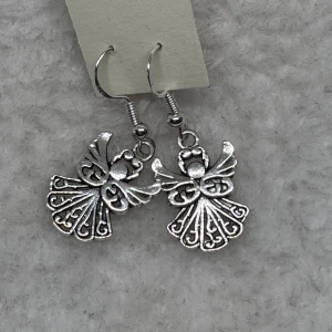 Silvriga ängelörhängen - Ett par snygga örhängen i silverfärgad metall med detaljerade ängelmotiv. Hängande modell med fina utskurna mönster som ger en unik och cool look. Perfekta för dig som vill sticka ut lite extra. Krokarna är i sterling silver 