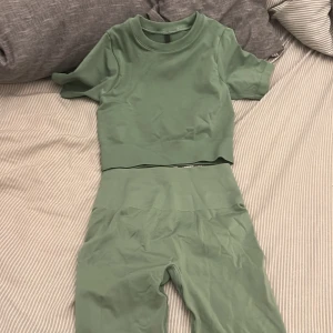 Gröna träningstights-top från Bo+Tee - Snygga gröna träningstights-top från Bo+Tee i seamless modell. Högmidjade med ribbad kant och scrunch-detalj bak för extra shaping. Materialet är en blandning av polyamid, polyester och elastan som ger bra stretch och komfort. Perfekta för gymmet eller sport. Storlek xs 