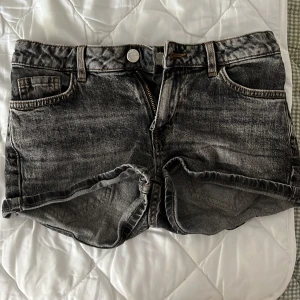 Grå jeansshorts från Lindex - Snygga lågmidjade grå jeansshorts från Lindex med klassisk femficksdesign, uppvikta benslut och dragkedja framtill. Perfekta för sommardagar och enkla att matcha med allt. Stentvättad look för en cool vibe.