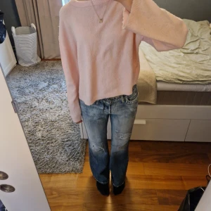 Lågmidjade bootcut jeans med slitningar - Säljer ett par lågmidjade jeans med bootcut passform och slitna detaljer på både fram- och baksida. 