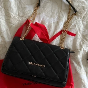 Svart quiltad axelväska från Valentino - Säljer en svart quiltad axelväska från Valentino med guldfärgade kedjor och logga framtill. Väskan är oanvänd nästan som ny. 🤍🤍