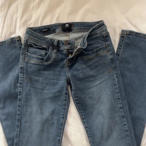 Blå jeans LTB Valerie W25 L32 - Snygga blå jeans från LTB, modell Valerie. Klassisk femficksdesign med raka ben och normal passform. Jeansen har mellanblå tvätt och detaljerade bakfickor. Perfekta till vardags och lätta att matcha med olika stilar.