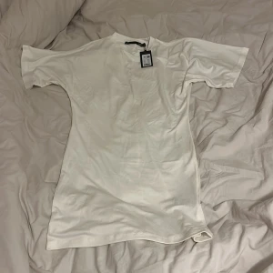 Vit t-shirtklänning  - Säljer en vit t-shirtklänning från Lager 157 i storlek XS. Modellen heter Lucy och har korta ärmar och är gjord i mjuk bomull. Passformen är normal och klänningen är enkel och stilren utan mönster eller detaljer. Helt ny med prislapp! 