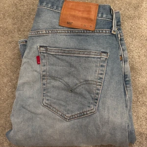 Levi's 501 ljusblå jeans straight fit - Ljusblå Levi's 501 jeans med klassisk straight fit. Jeansen har en snygg tvättad look och är lite stretchiga. Jeansen är använda men skulle säga 8/10 i cond. Storlek W31 L30 som ni ser på bilden, passar mig perfekt som är 180cm och väger 70kg